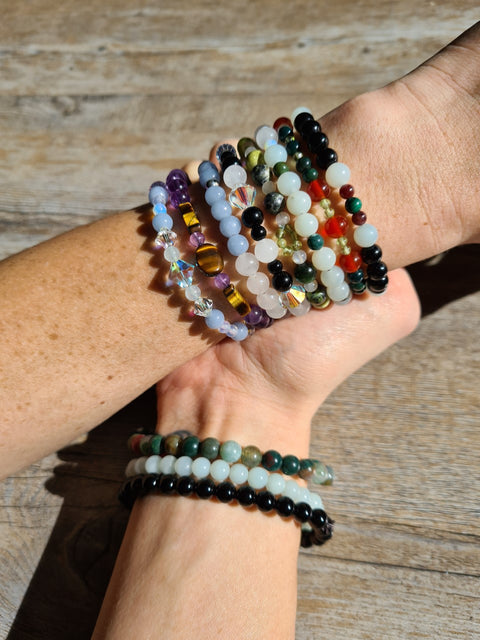 Variety of crystal gemstone bracelets on a woman's arms