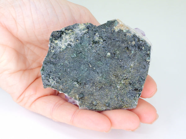 The bottom of a beautiful Amethyst cluster with inclusions in someone's hand. Bottom view