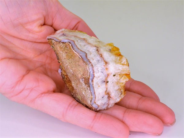 The bottom of a beautiful Citrine cluster with inclusions in someone's hand. Bottom view