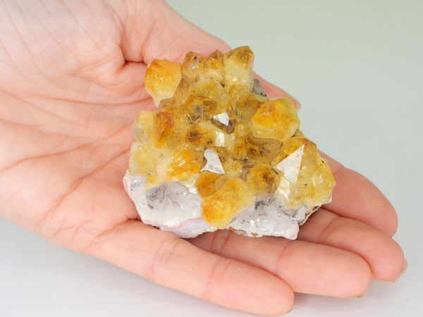 Beautiful Citrine cluster with inclusions in someone's hand. Top view