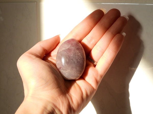 Purple Rose Quartz palm stone in someone's hand