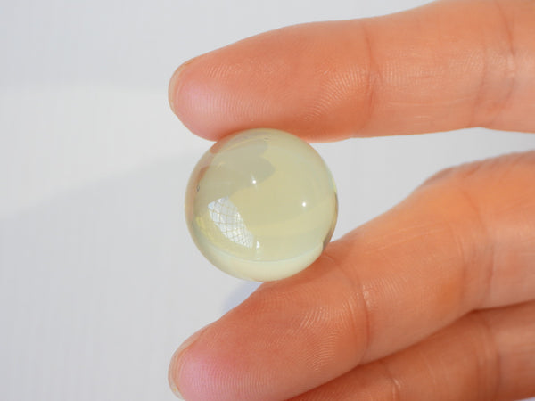 Star Citrine sphere inbetween someone's fingers, 11g size